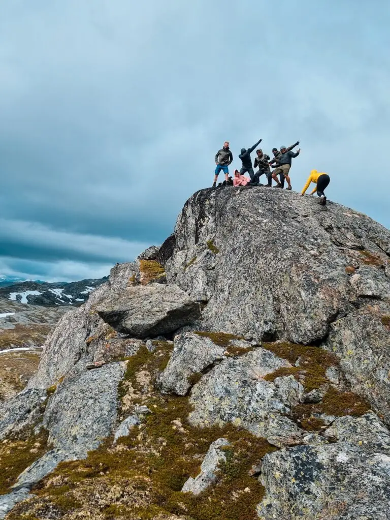 group of friends posing on a mountain peak in Norway