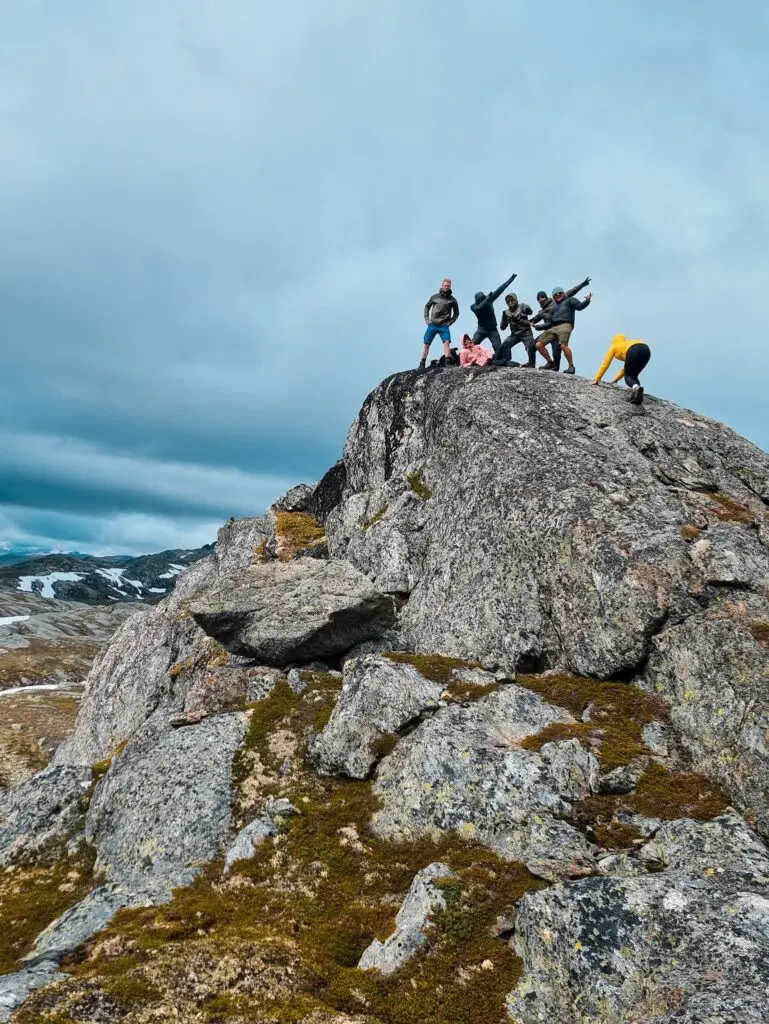 group of friends posing on a mountain peak in Norway