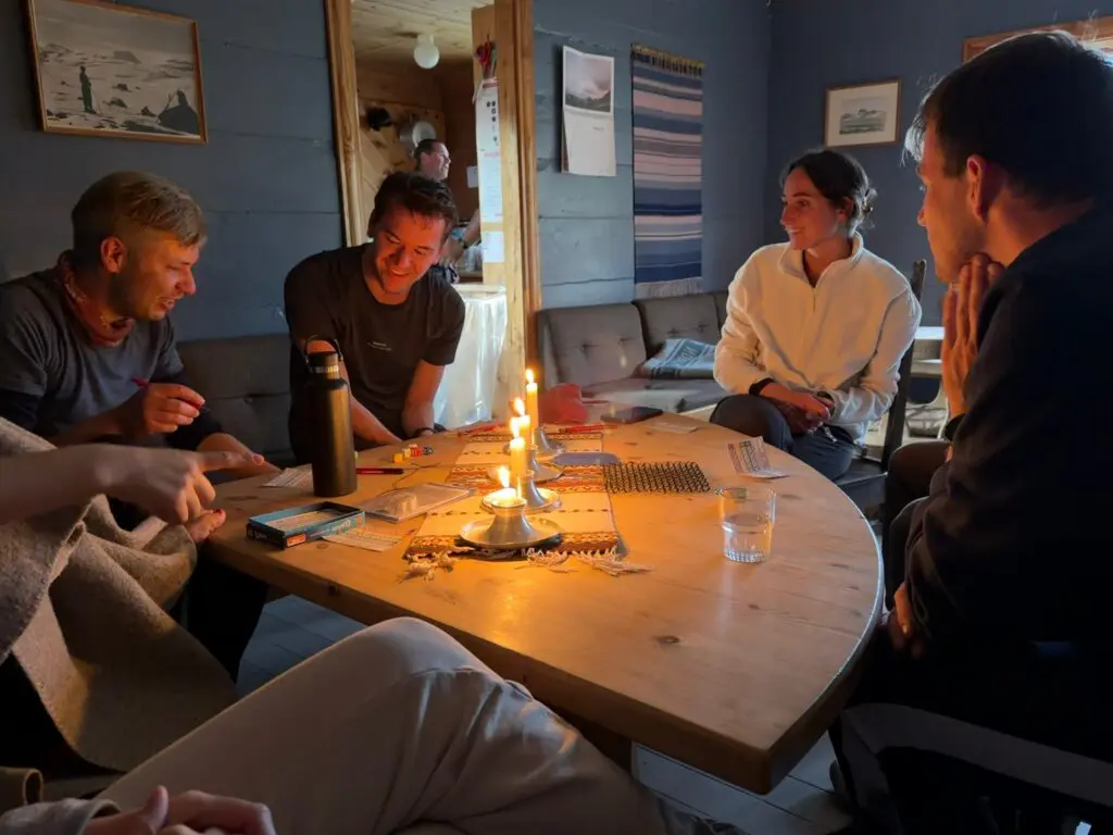 group of friends playing board games by candlelight in a cozy cabin