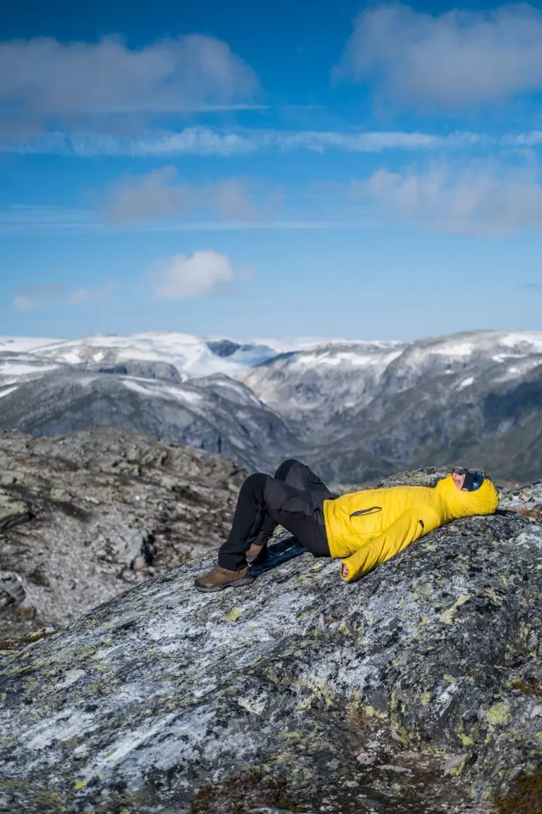 hiker relaxing on rock with snowy mountains in Norway