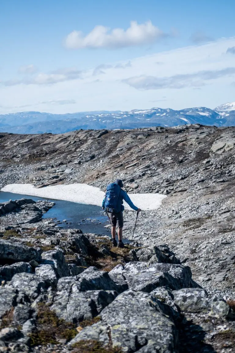 hiker with backpack and trekking pole on rocky trail in Norway