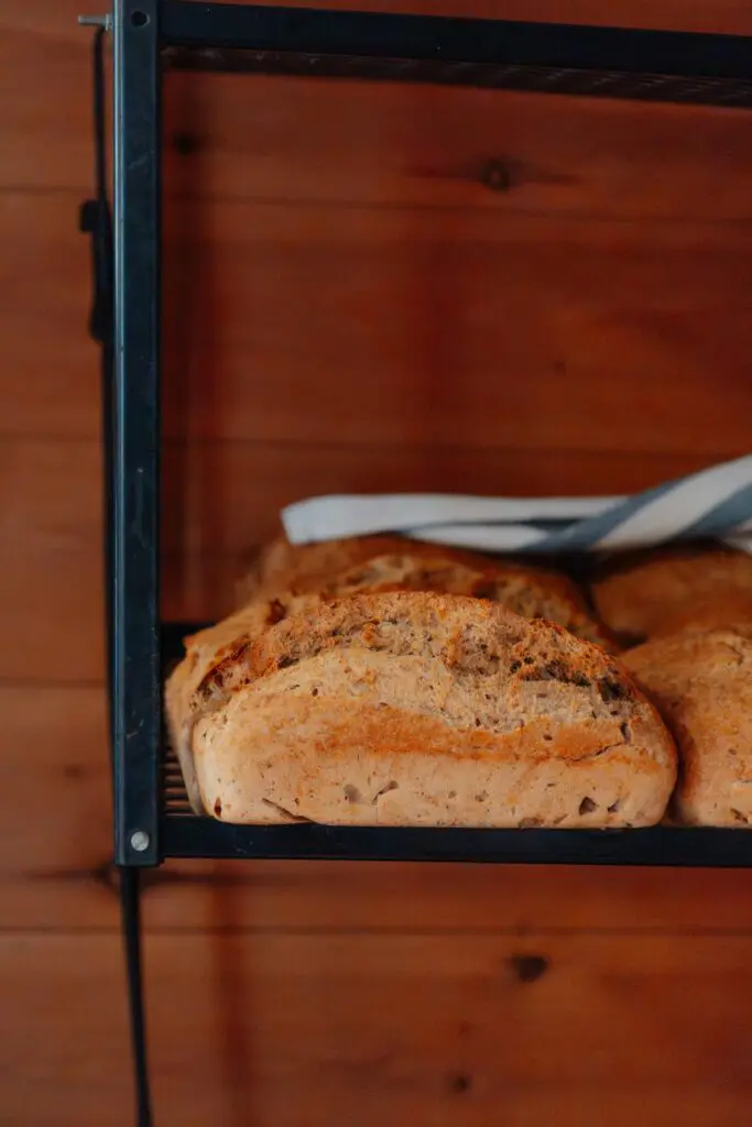 freshly baked bread loaves on a shelf with wooden background