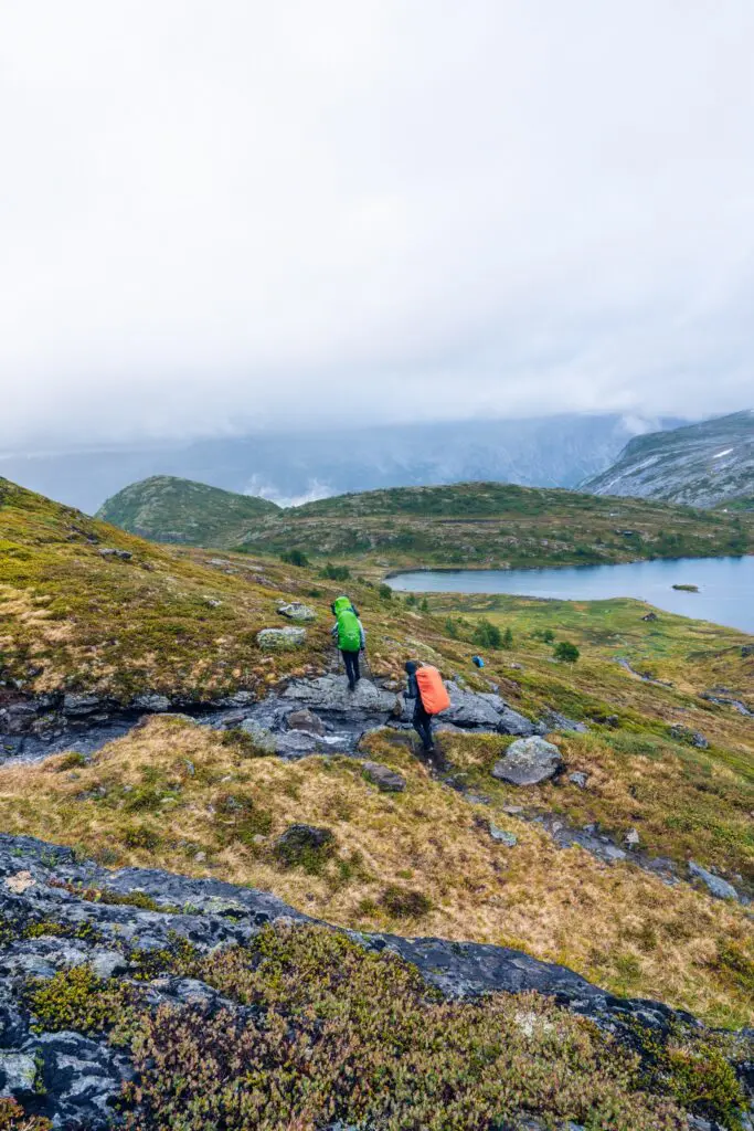 two hikers with backpacks on a rocky trail in Norway