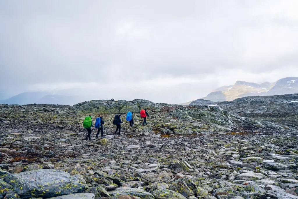 hikers with colorful backpacks on a rocky mountain trail in Norway