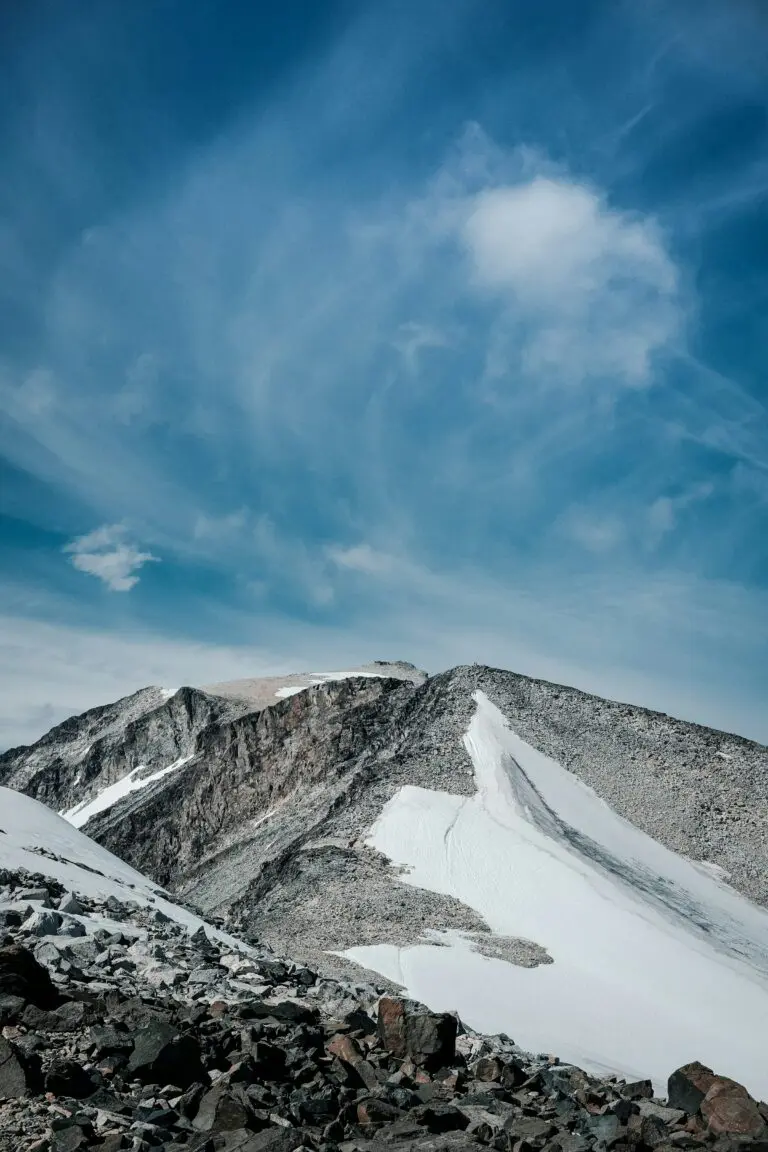 A snow covered mountain under a cloudy blue sky